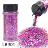 A purple holographic chunky nail glitter mix in a glass shaker bottle being poured out onto a surface.