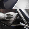 A black microfiber car drying towel is shown being used to wipe a car's exterior surface.