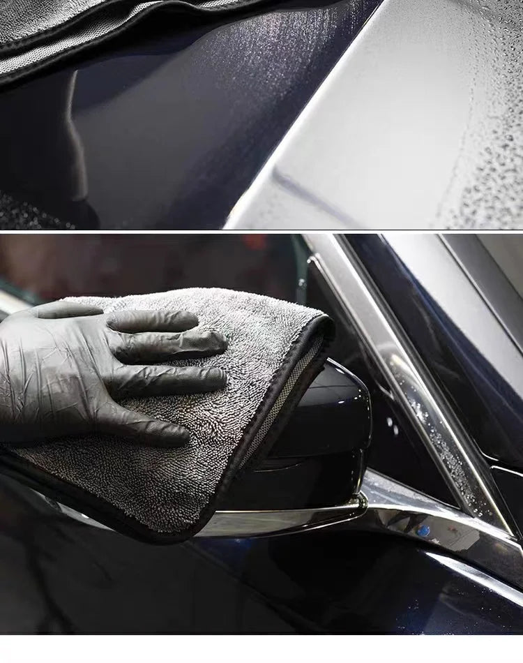 A black microfiber car drying towel is shown being used to wipe a car's exterior surface.