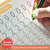 A hand writes numbers and letters in a grid-lined practice book with a green pen.