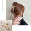 Nahaufnahme von Frauenhaar, elegant im Dutt mit goldener geometrischer Haarspange.