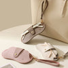 A light pink PU leather glasses case with a lychee pattern and gold hardware resting on a beige background.