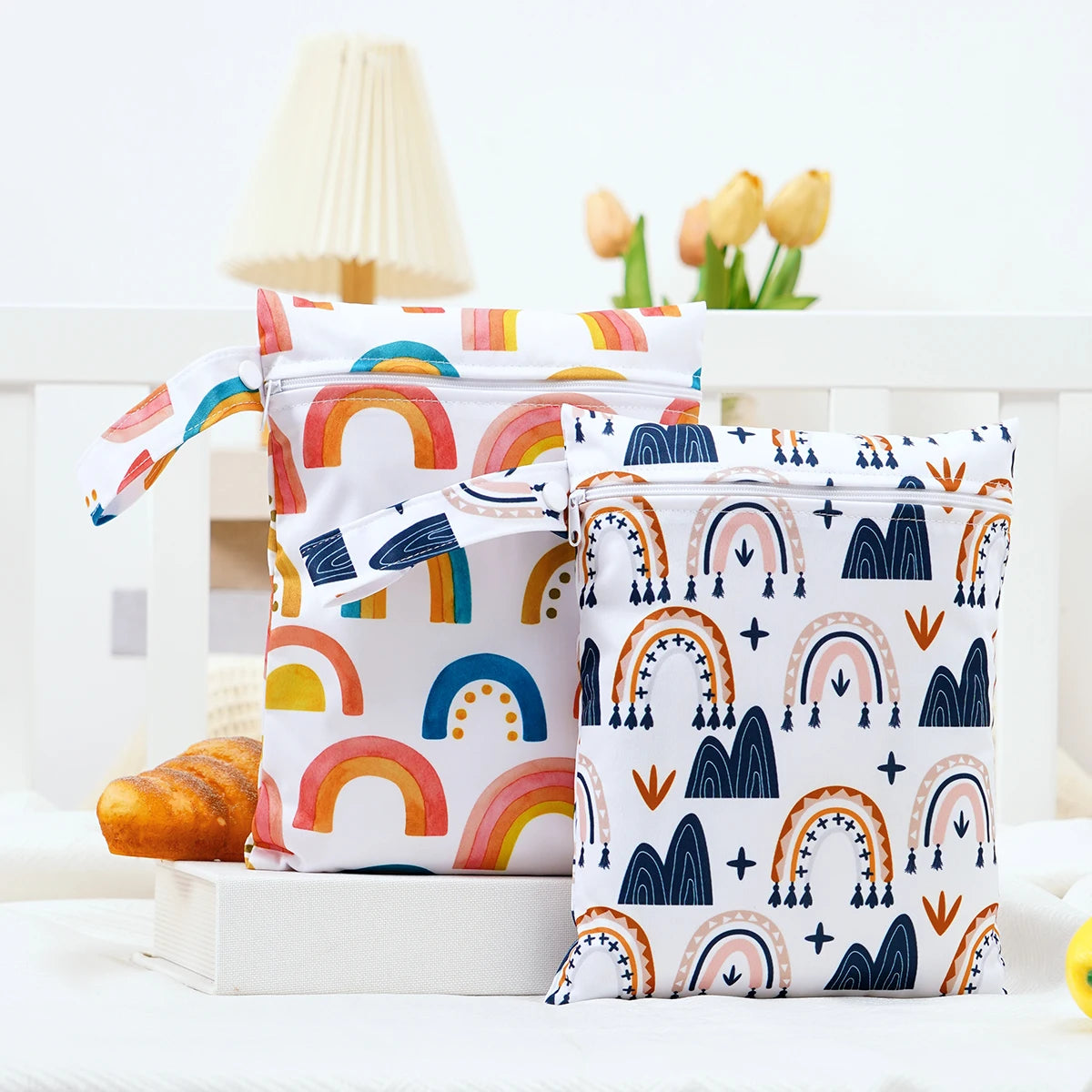 A pair of colorful rainbow patterned mini waterproof wet dry bags for baby are displayed on a white surface.
