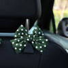 A dark green bow-shaped car seat back hook with storage attached to a black car seat.