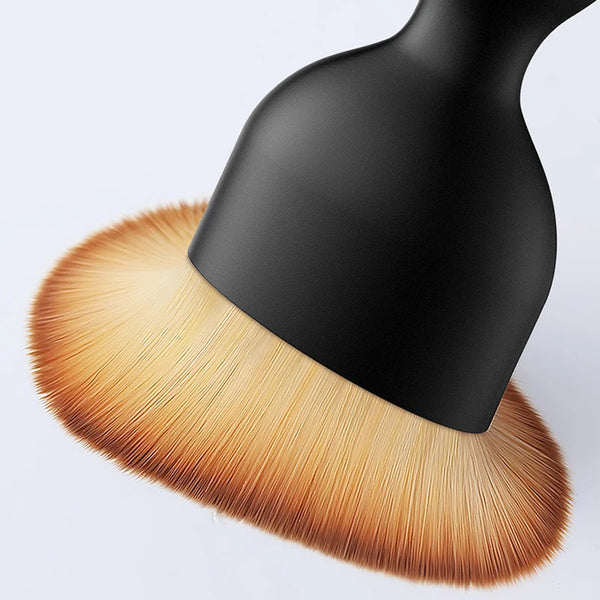 Gros plan d'une brosse nettoyante pour aération de voiture noire avec des poils dorés.