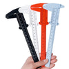 A hand holds a plastic vernier caliper tool with four different colored measuring scales.