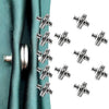 Silver magnetic curtain clips scattered on a white background with a teal fabric in the background