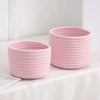 A pink handwoven cotton rope storage basket with a textured weave sits on a white surface.