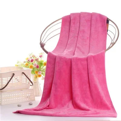 A bright pink ultra-soft microfiber bath towel draped over a metal hanger.