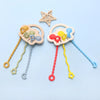 A silicone bear teether with a textured pull string and a star-shaped silicone toy on a light blue background.
