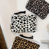 A close-up of three leopard print cosmetic bags in black and white patterns displayed on a white surface.