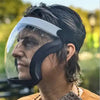 A man wearing a full face anti-fog splash shield with an adjustable strap, looking to the side outdoors.