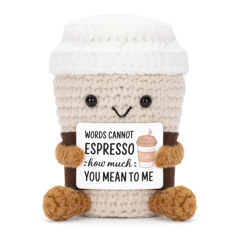 A handmade crochet animal doll with a light beige body and white hat, holding a card that reads Words cannot espresso how muc