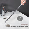 A hand is using a flexible drain cleaning brush with spiral bristles to clean a kitchen faucet.