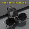 A pair of black sunglasses is clipped onto a black visor glass holder.
