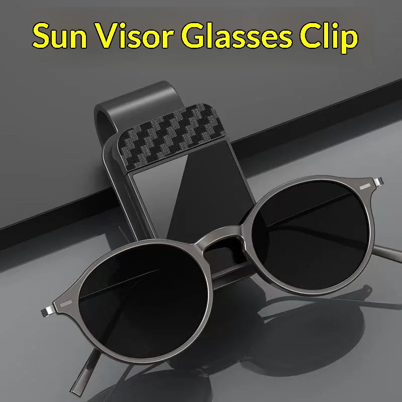 A pair of black sunglasses is clipped onto a black visor glass holder.