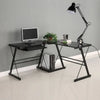 A black adjustable swing arm desk lamp mounted on a black metal desk frame with a computer monitor and books.