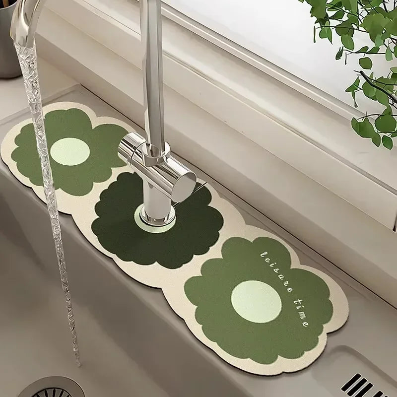 A faucet mat with a green floral design is placed in a sink, featuring a chrome faucet.