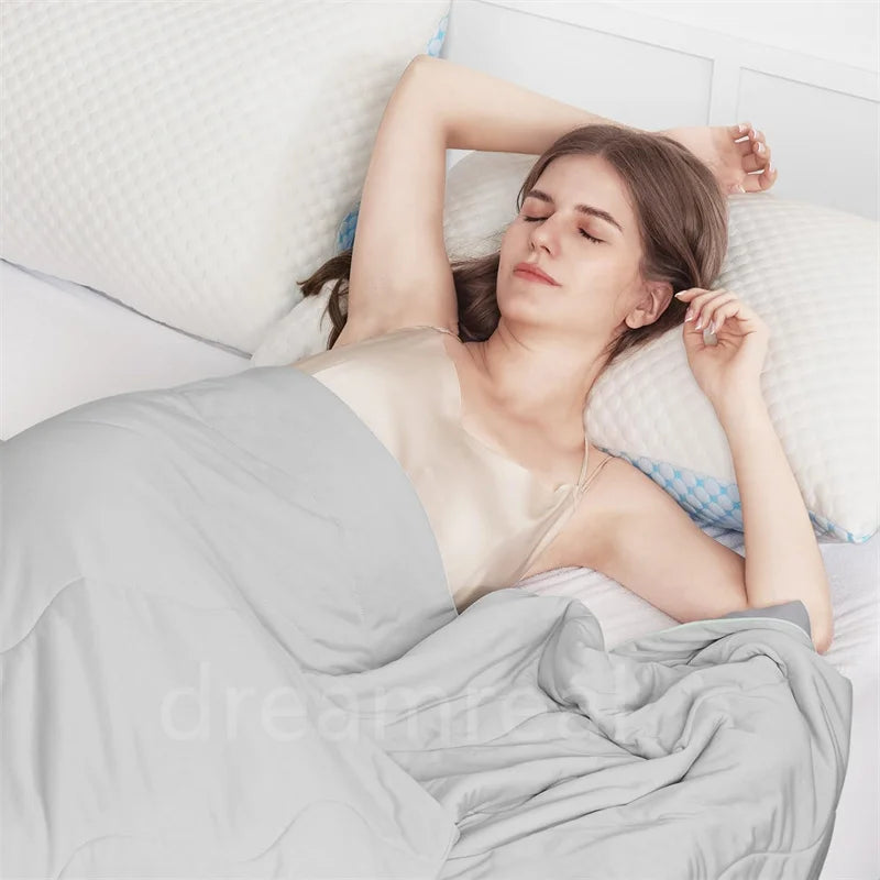 A woman is lying in bed under a light gray blanket, resting her head on a white pillow.