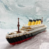 A detailed LEGO model kit of the Titanic ship featuring black, yellow, and white colors against a marbled background.