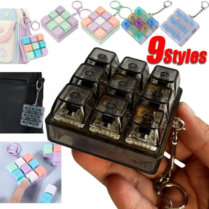 A hand holds a clear plastic keychain with multiple colored tactile clicking buttons and a metal keyring.