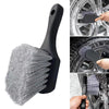 A black compact brush used for cleaning car wheels and tires.