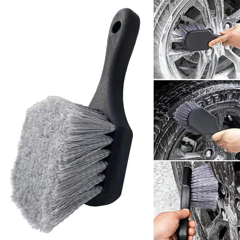 A black compact brush used for cleaning car wheels and tires.
