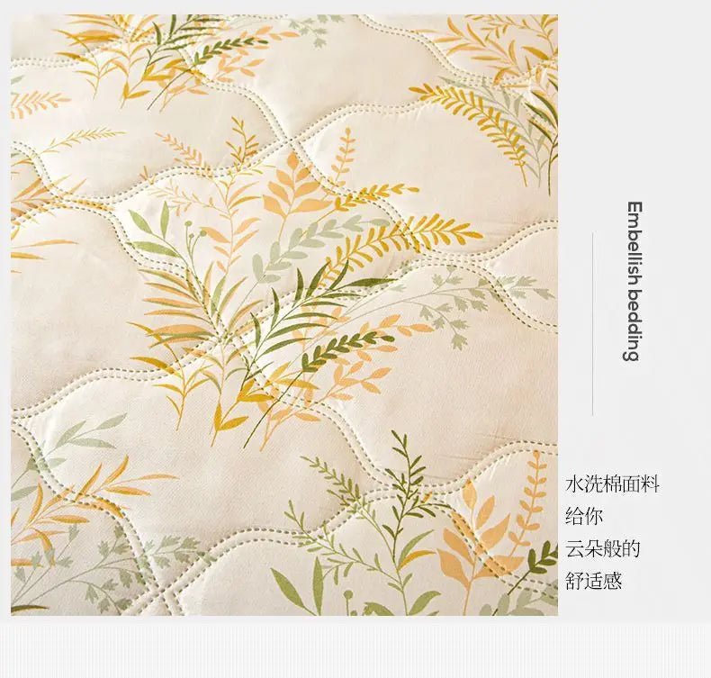 A close-up of a beige quilted fabric featuring delicate yellow and green botanical embroidery for bedding.