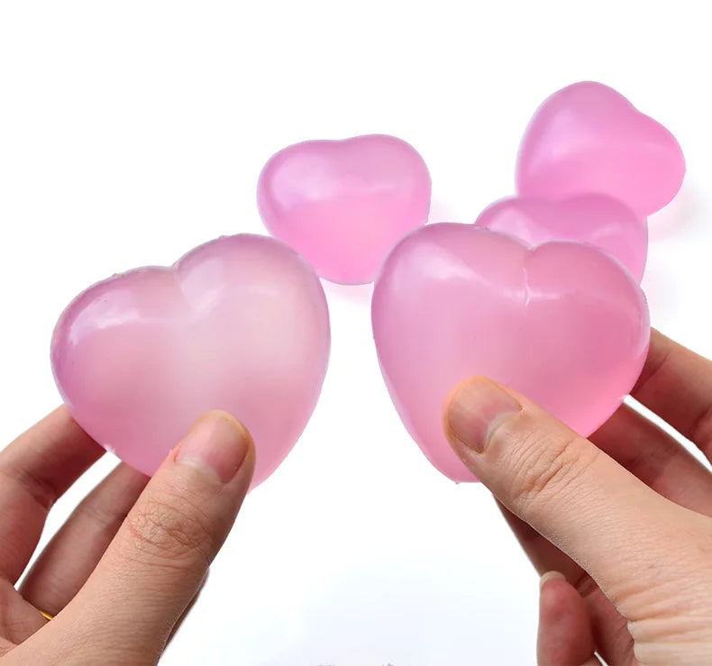 Pink heart-shaped stress relief squeeze toy being held in a hand