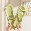 A pair of light green foldable EVA travel slippers being held by hands against a light background.