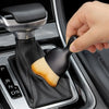 A hand is using an ultra-soft curved detailing brush with a wooden handle to clean car vents or gaps.