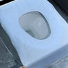 A white disposable toilet seat cover is shown resting on a light blue cloth surface.