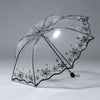A clear, retro transparent arch umbrella with a floral design is shown against a light gray background.