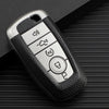 Silver TPU leather car key cover with multiple buttons and a key inside, resting on a dark surface.