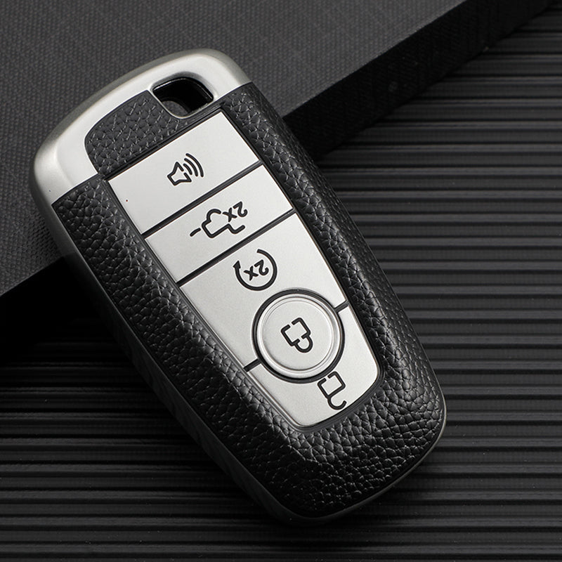 Silver TPU leather car key cover with multiple buttons and a key inside, resting on a dark surface.