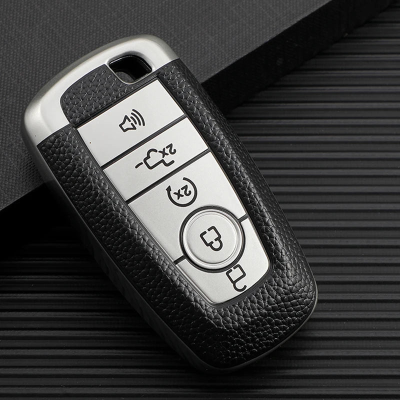 A silver TPU leather car key cover with multiple buttons rests on a dark textured surface.
