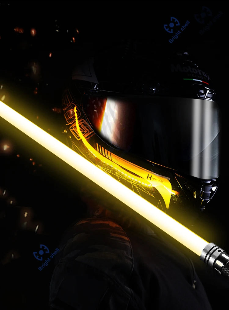 A person holding a yellow lightsaber with bright glow against a dark background.