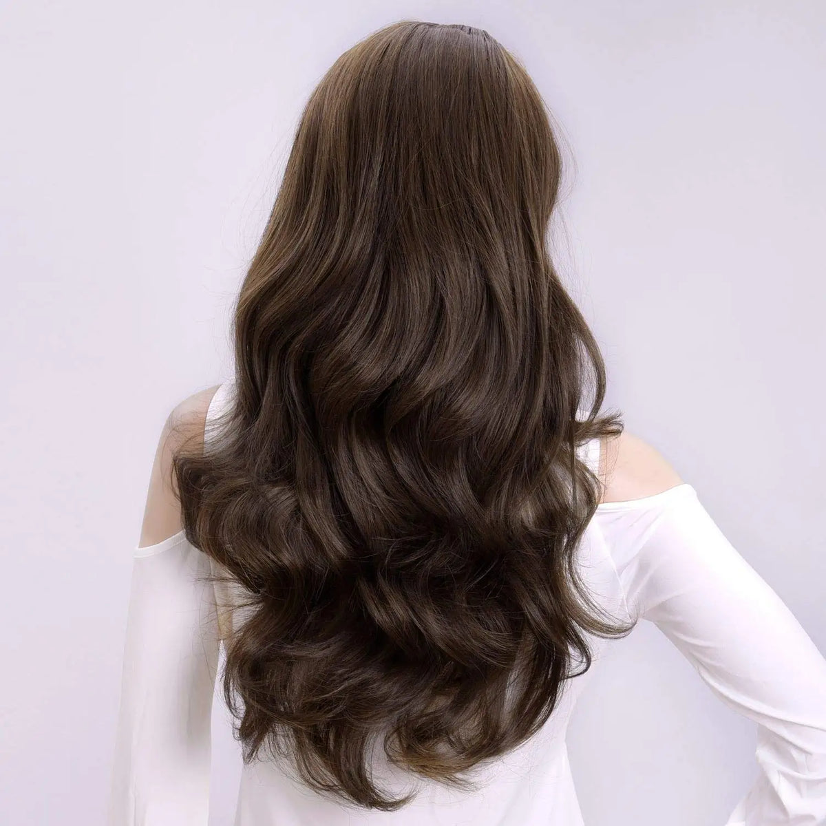 A long, wavy brown wig displayed on a mannequin, shown from the back.