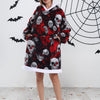 Eine Frau modelliert einen oversized Fleece-Hoodie mit Schädelmuster in schwarz und rot vor einer weißen Wand mit Spinnweben-