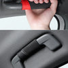 A hand is holding a black grab handle protector cover for a car, showing its installation and design.