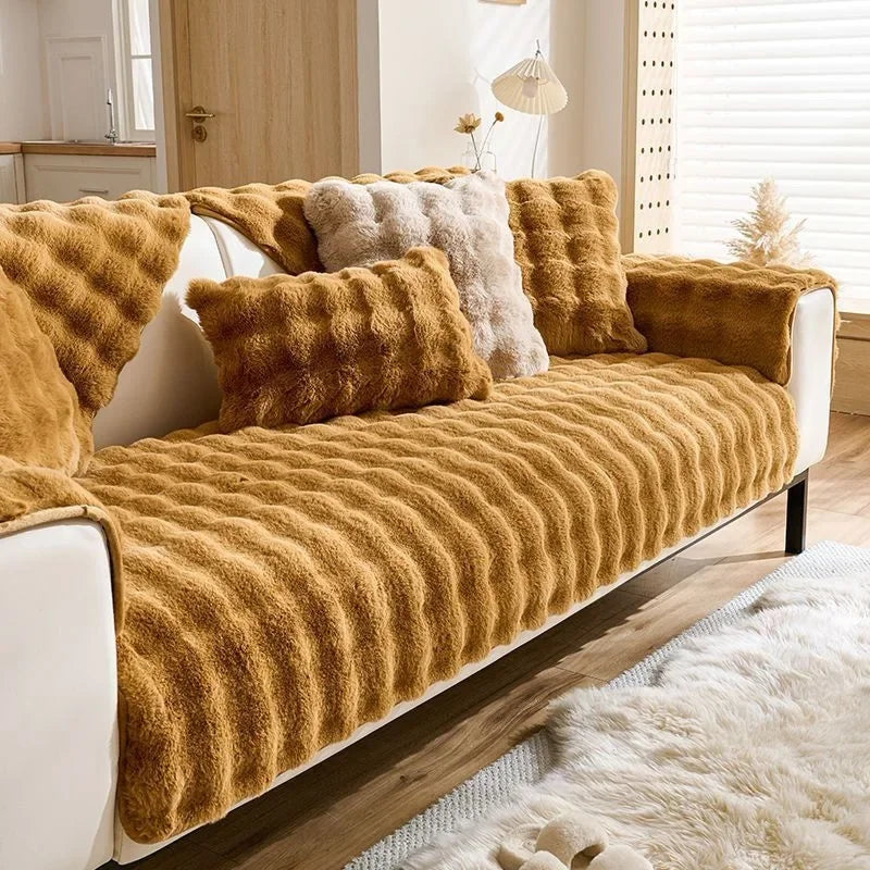 Senfgelbes Plüschkaninchen-Sofa-Kissen mit flauschigen Akzenten auf einem weißen Sofa.