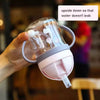 A hand holds a clear plastic straw cup with handles upside down to prevent leakage.