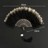 A vintage lace folding hand fan with a black and gold feathered design shown against a dark background.