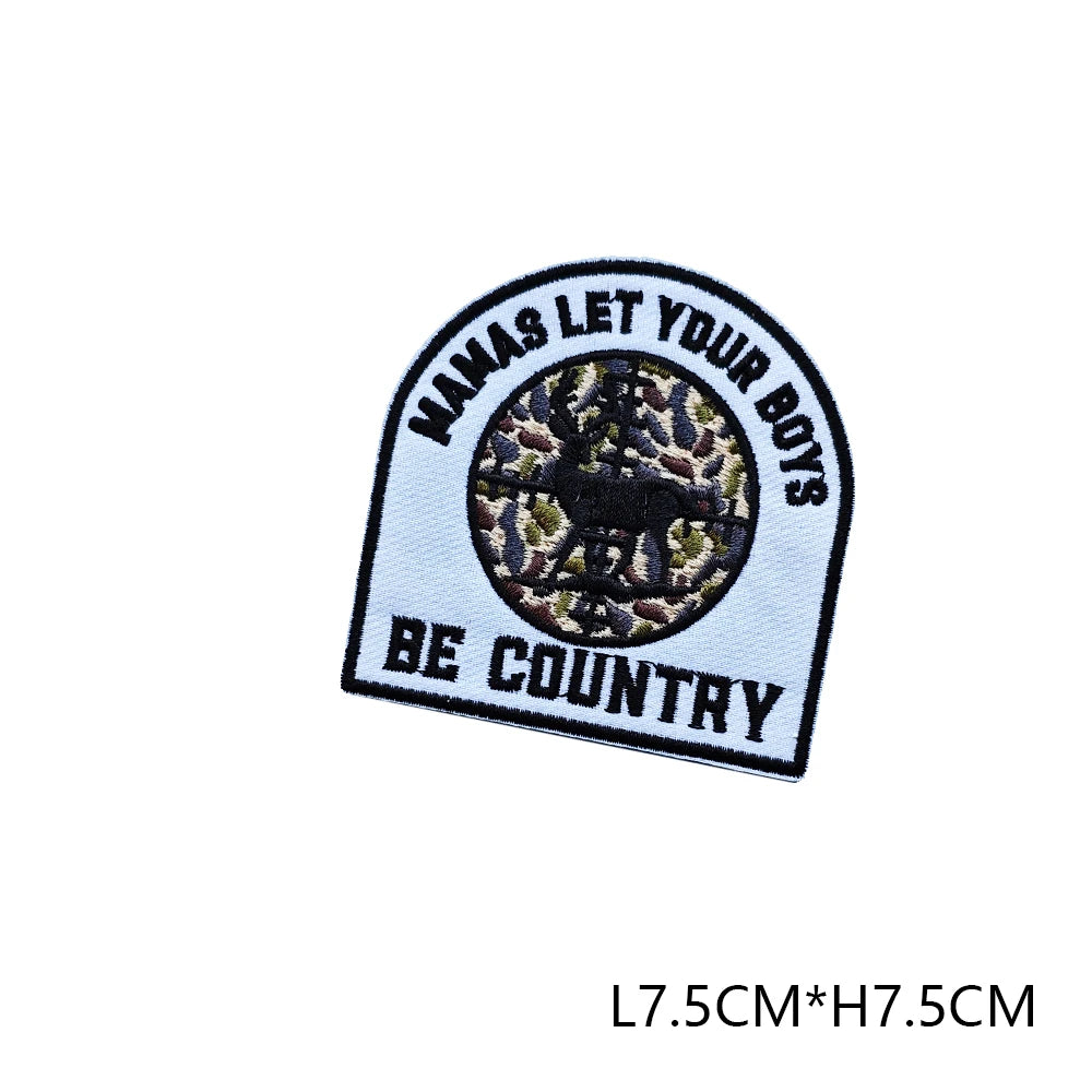 Black and white embroidered patch with text NAMAS LET YOUR BOYS BE COUNTRY surrounding a circular hunting motif