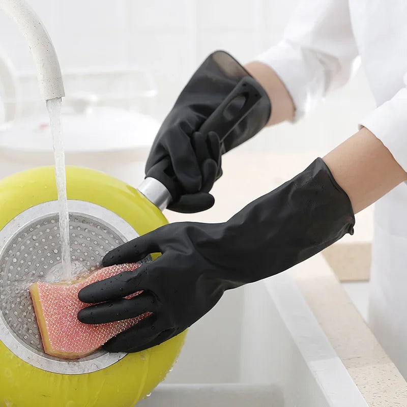 A hand wearing a black rubber cleaning glove is using it to clean a textured pink object in a yellow basin.
