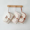 A white quilted foldable portable diaper changing pad is hanging on a wooden rack.