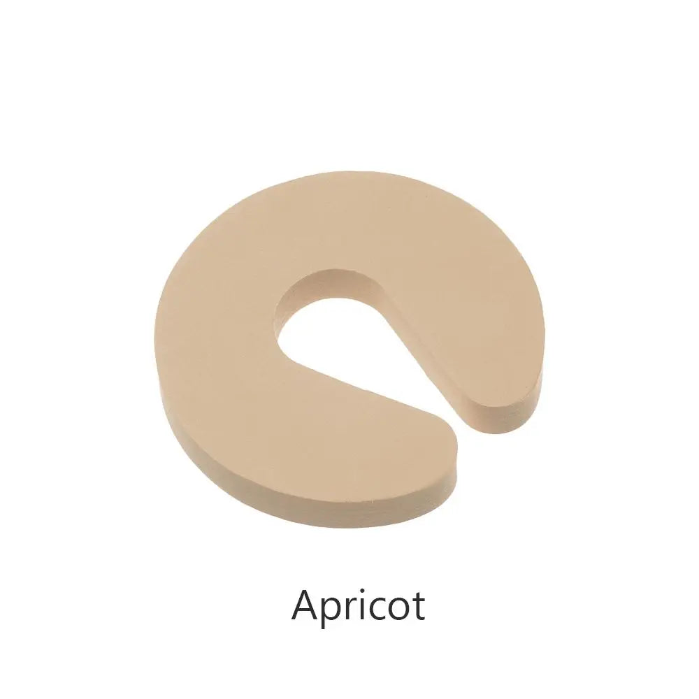 A beige foam door stopper with a curved shape designed for finger pinch protection.