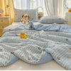 Light blue and white striped quilt with playful cartoon animal prints on a bed