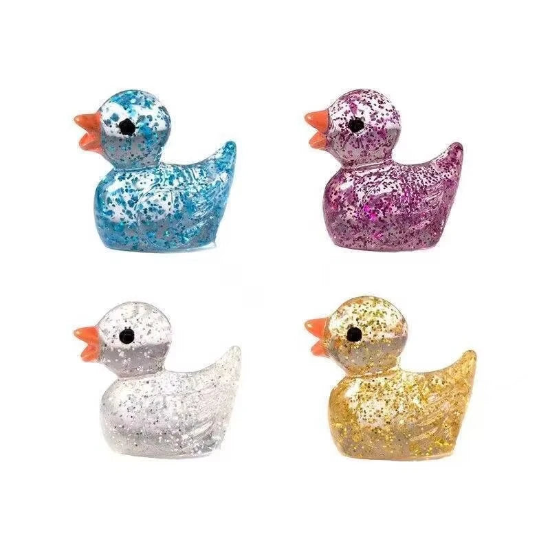 A set of four glitter resin duck figurines in blue, purple, silver, and gold.