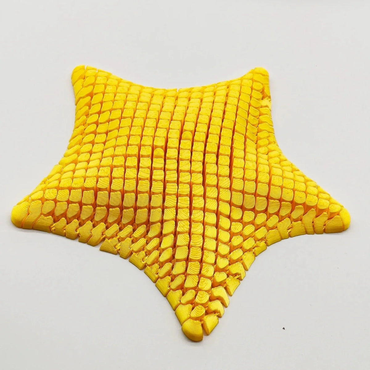 A bright yellow 3D printed articulated starfish fidget toy with a textured, grid-like surface.